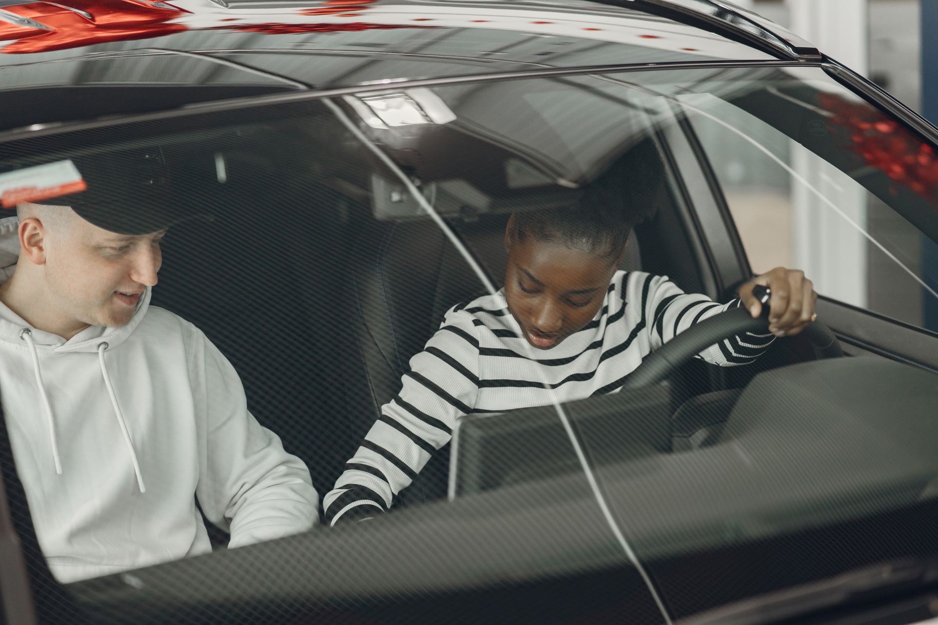 An instructor and a learner sitting in a car, talking through a lesson