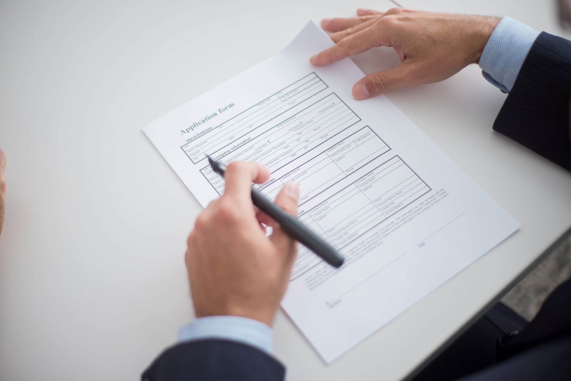 A person filling out a licence application form at a desk
