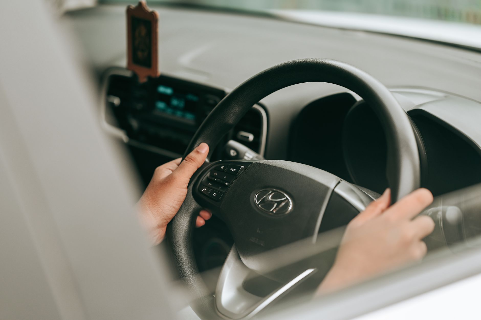 A learner's hands placed on a car steering wheel during a driving lesson