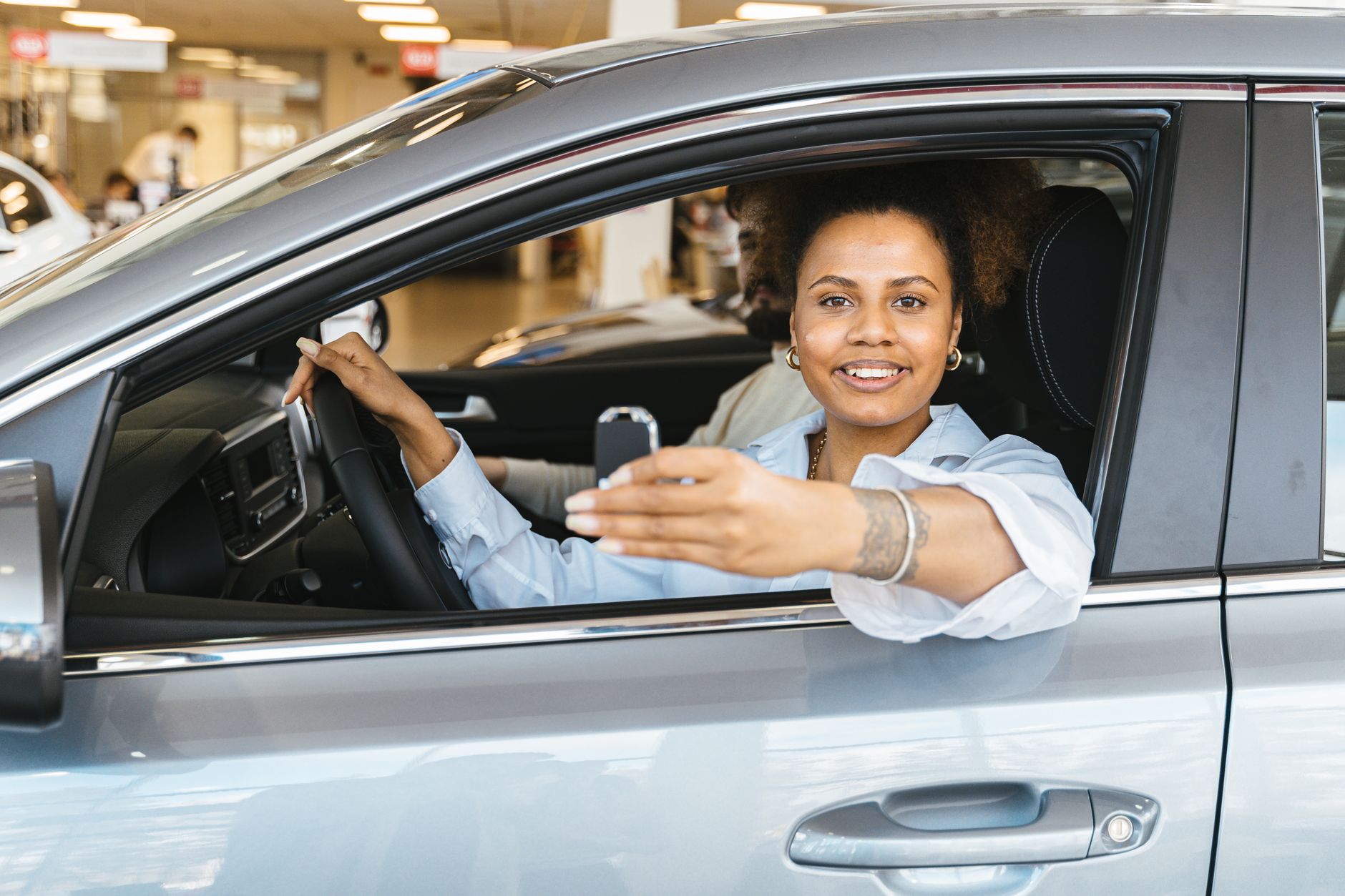 A person sitting in a car holding their keys, relieved after a driving test